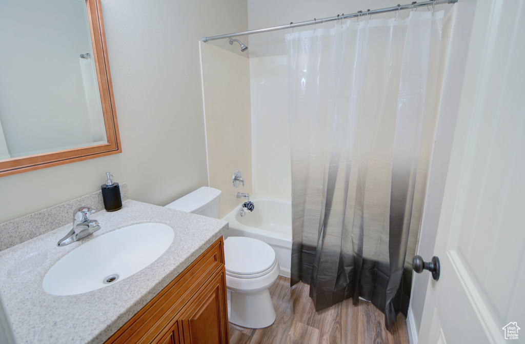 Full bathroom featuring vanity, toilet, hardwood / wood-style flooring, and shower / tub combo with curtain