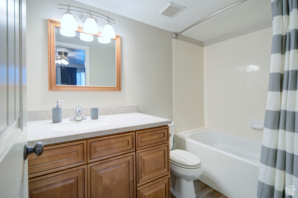 Full bathroom featuring hardwood / wood-style floors, shower / bath combo with shower curtain, toilet, and vanity