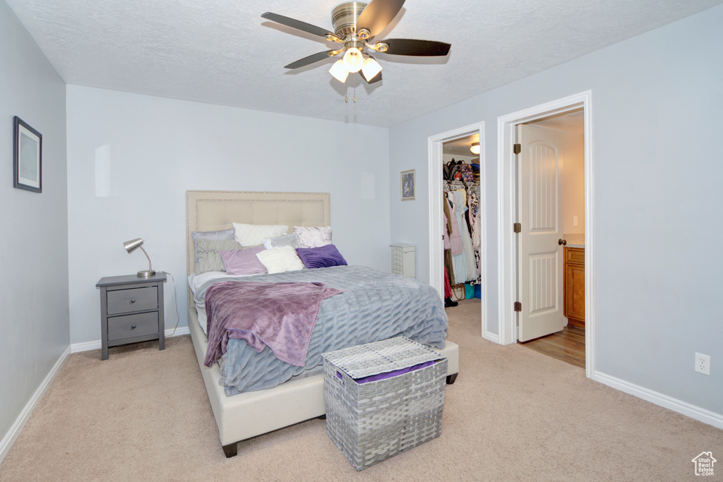 Carpeted bedroom featuring a walk in closet, a closet, a textured ceiling, and ceiling fan