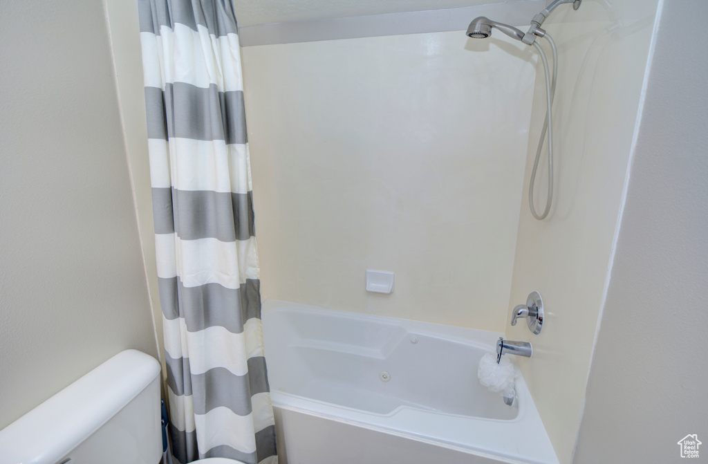 Bathroom with shower / bath combination with curtain and toilet