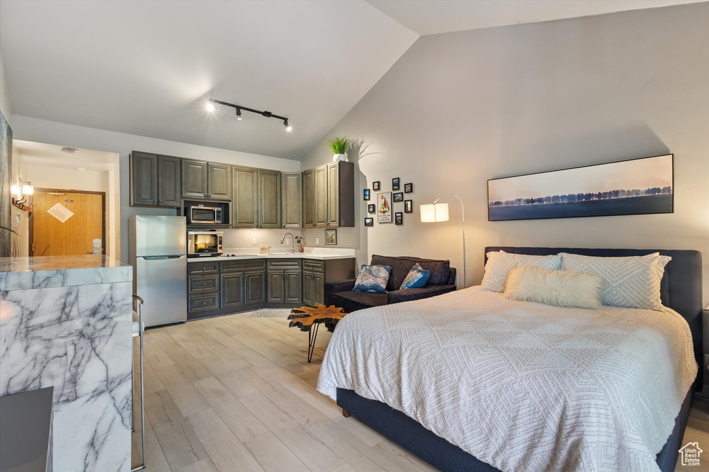 Bedroom with light hardwood / wood-style flooring, sink, rail lighting, stainless steel fridge, and ensuite bath