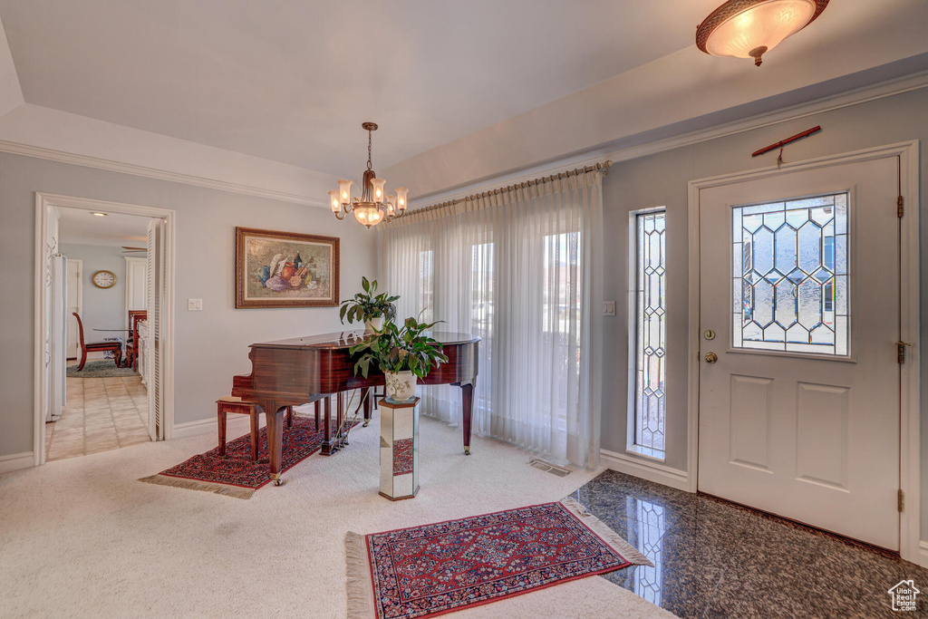 Carpeted foyer entrance with a notable chandelier and plenty of natural light