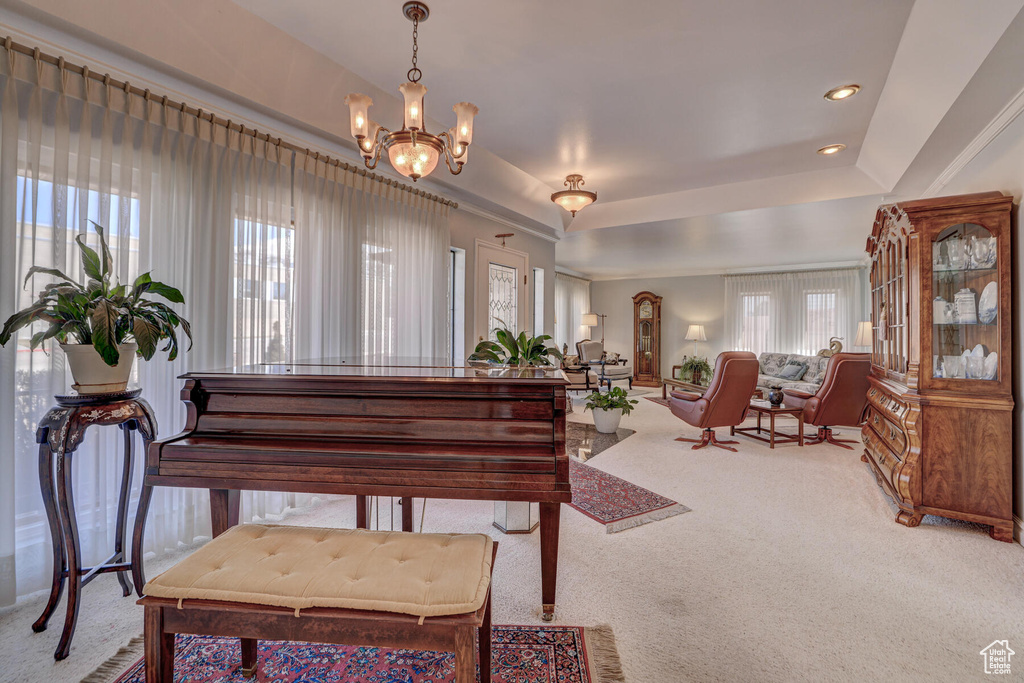 Misc room with an inviting chandelier, plenty of natural light, a tray ceiling, and carpet