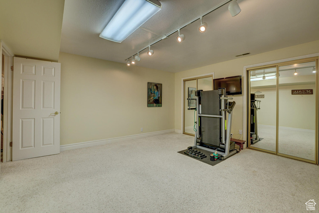 Workout room featuring track lighting and light colored carpet
