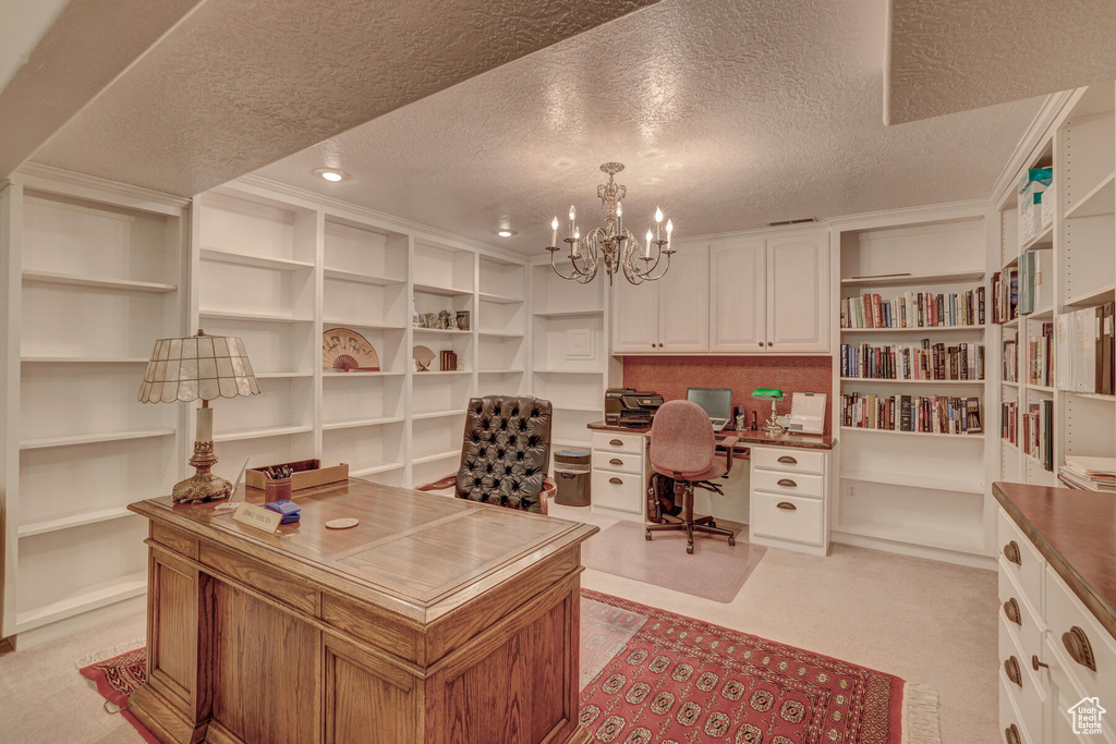 Home office with a notable chandelier, light carpet, a textured ceiling, and built in desk