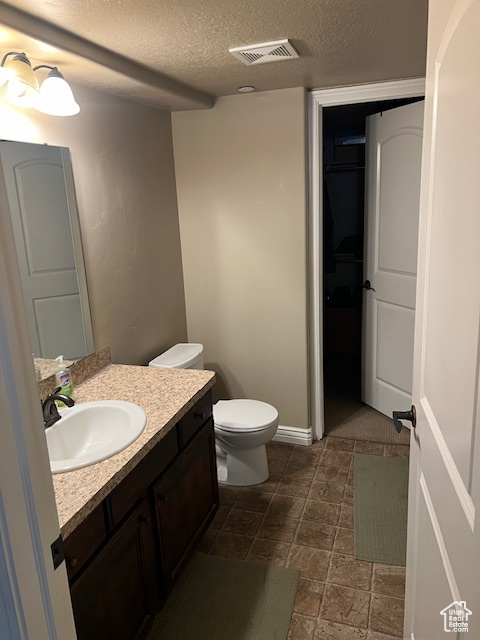Bathroom featuring a textured ceiling, toilet, tile flooring, and oversized vanity