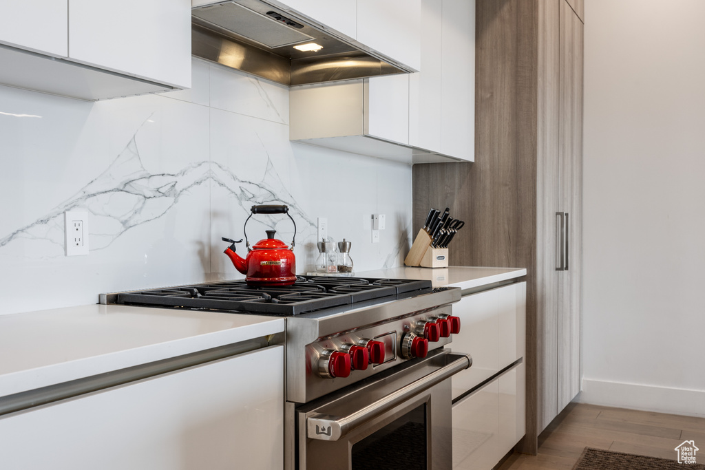 Kitchen featuring premium range hood, white cabinetry, light wood-type flooring, and designer range
