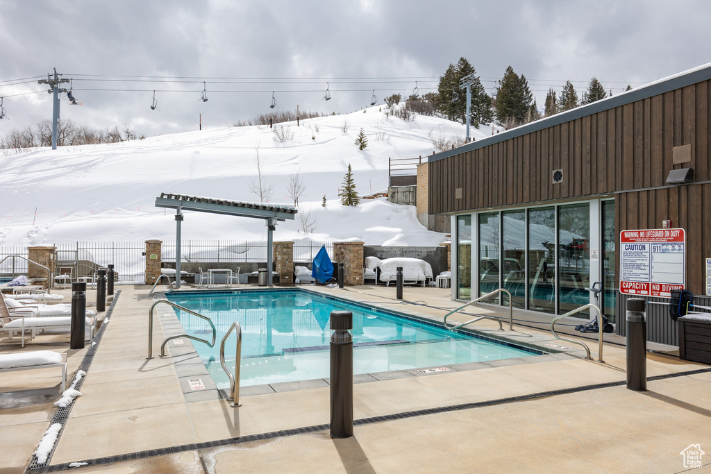 Snow covered pool featuring a patio