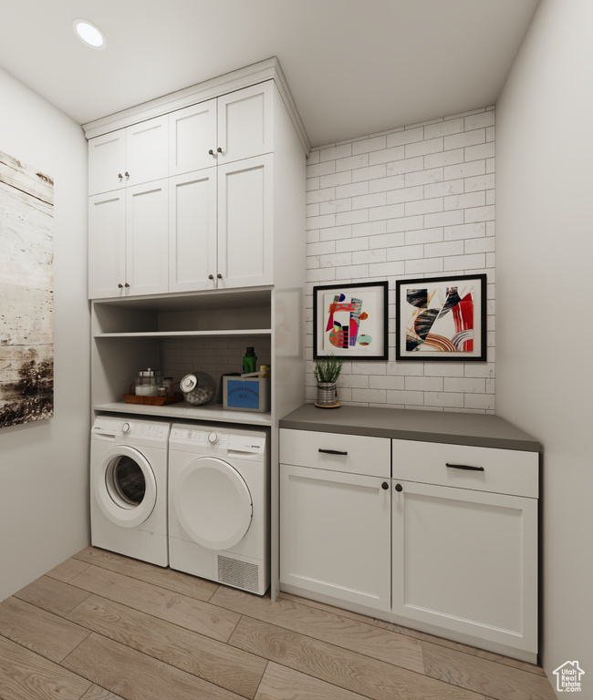 Washroom featuring washer and dryer, cabinets, and light hardwood / wood-style floors
