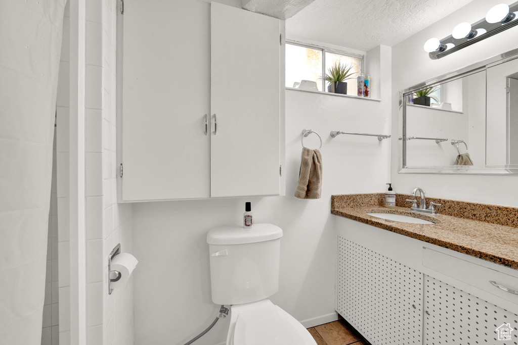 Bathroom featuring tile floors, a textured ceiling, large vanity, and toilet