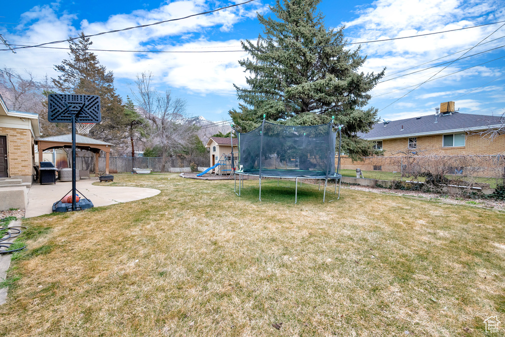 View of yard with a trampoline, a playground, a patio, and a gazebo