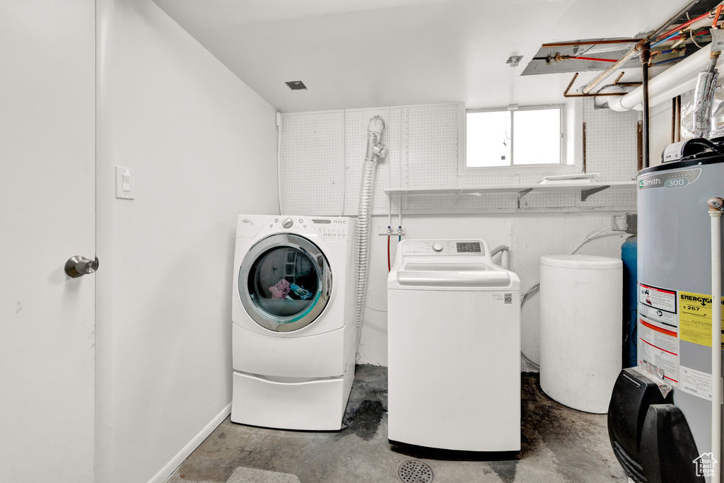 Clothes washing area featuring water heater and washing machine and clothes dryer