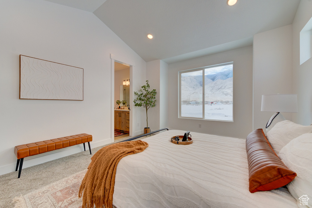 Bedroom featuring vaulted ceiling, light colored carpet, and ensuite bathroom