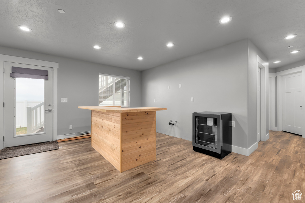 Bar featuring wine cooler, light wood-type flooring, a baseboard radiator, and plenty of natural light