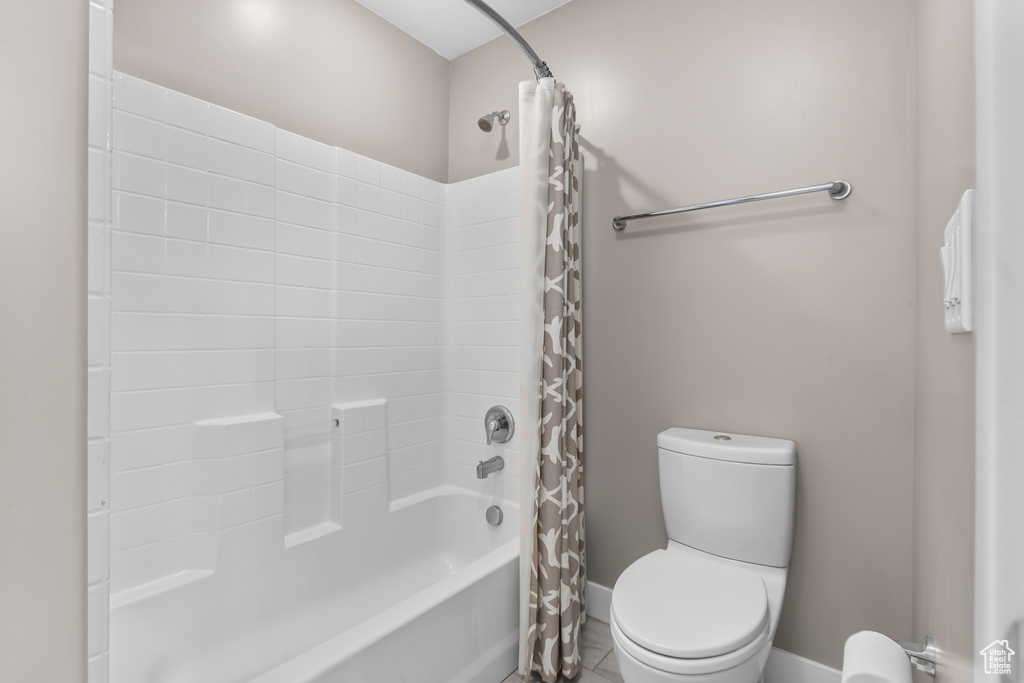 Bathroom with toilet, shower / bath combination with curtain, and tile floors