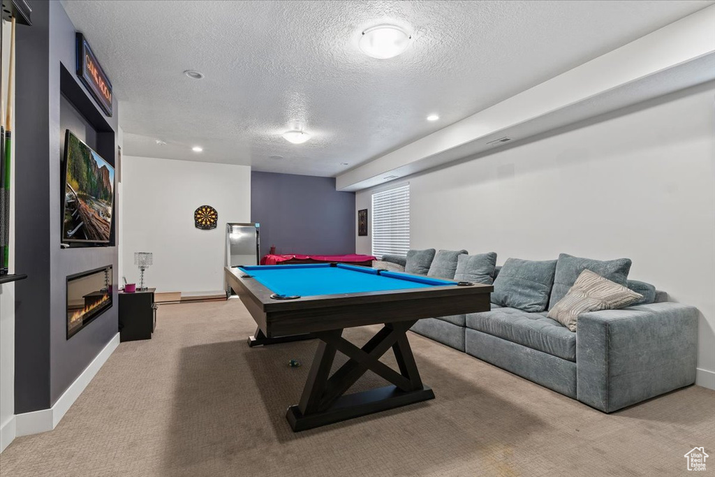 Recreation room featuring light colored carpet, a textured ceiling, and pool table