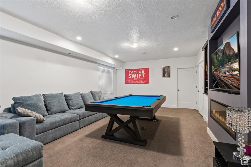 Game room with a textured ceiling, dark carpet, and pool table