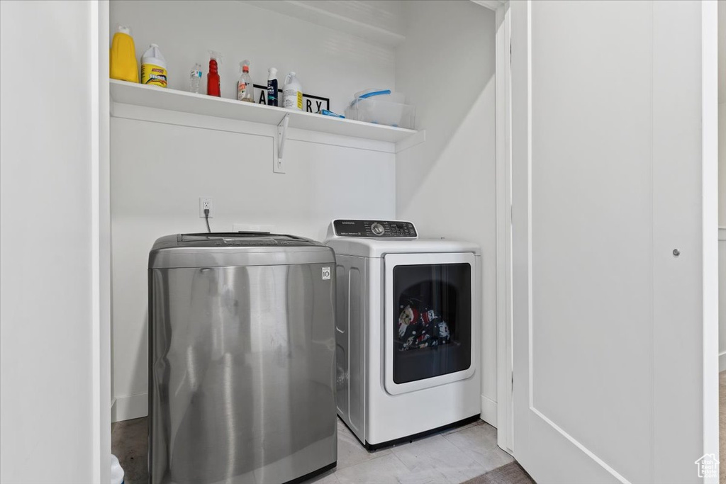 Clothes washing area with light tile floors and washing machine and clothes dryer