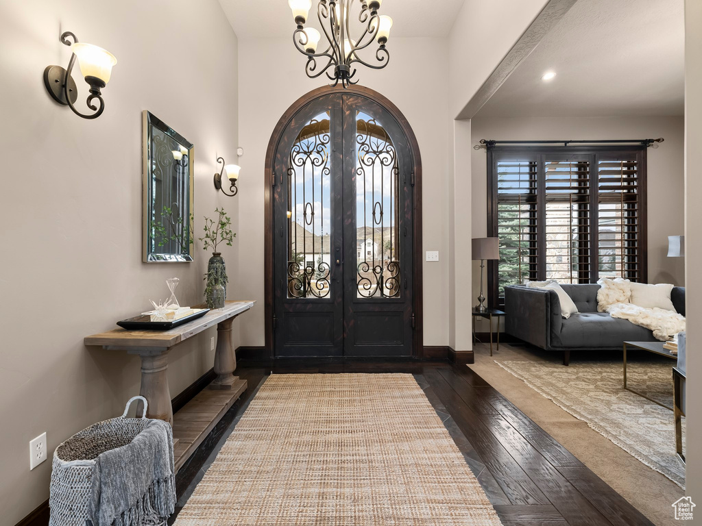 Foyer featuring an inviting chandelier, french doors, and dark wood-type flooring