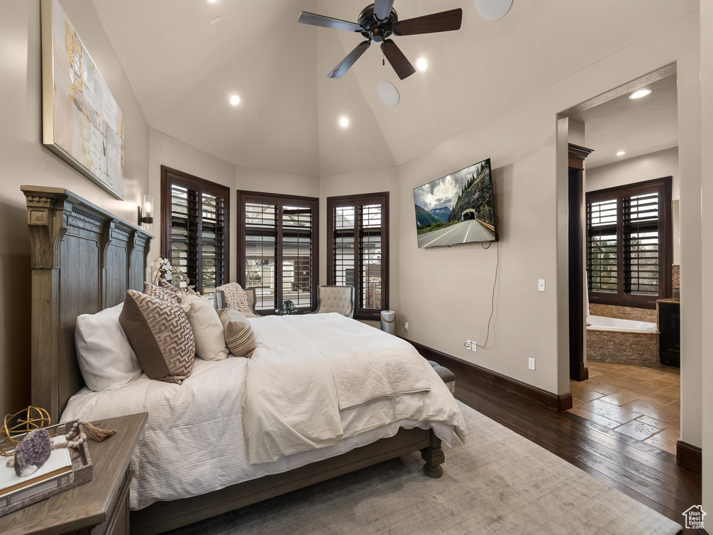 Bedroom with dark wood-type flooring, multiple windows, ensuite bathroom, and ceiling fan