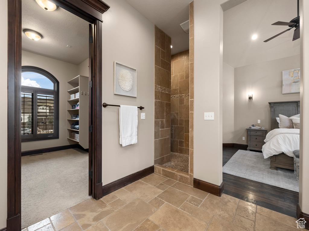 Bathroom featuring tiled shower, hardwood / wood-style floors, and ceiling fan