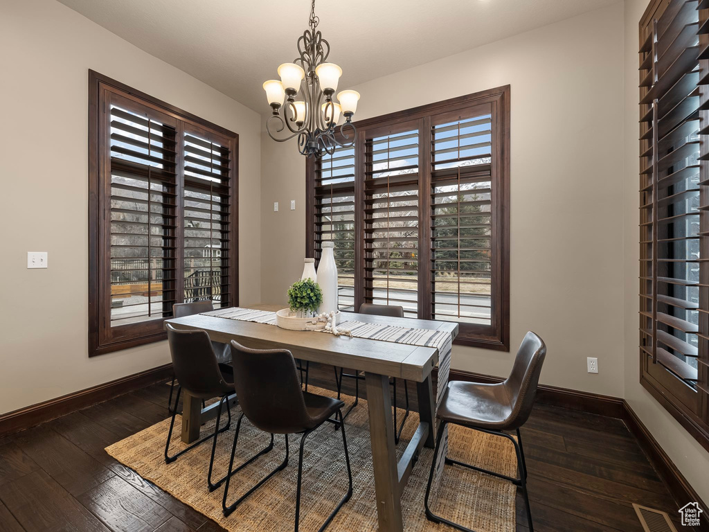 Dining room featuring a notable chandelier, dark hardwood / wood-style flooring, and a healthy amount of sunlight