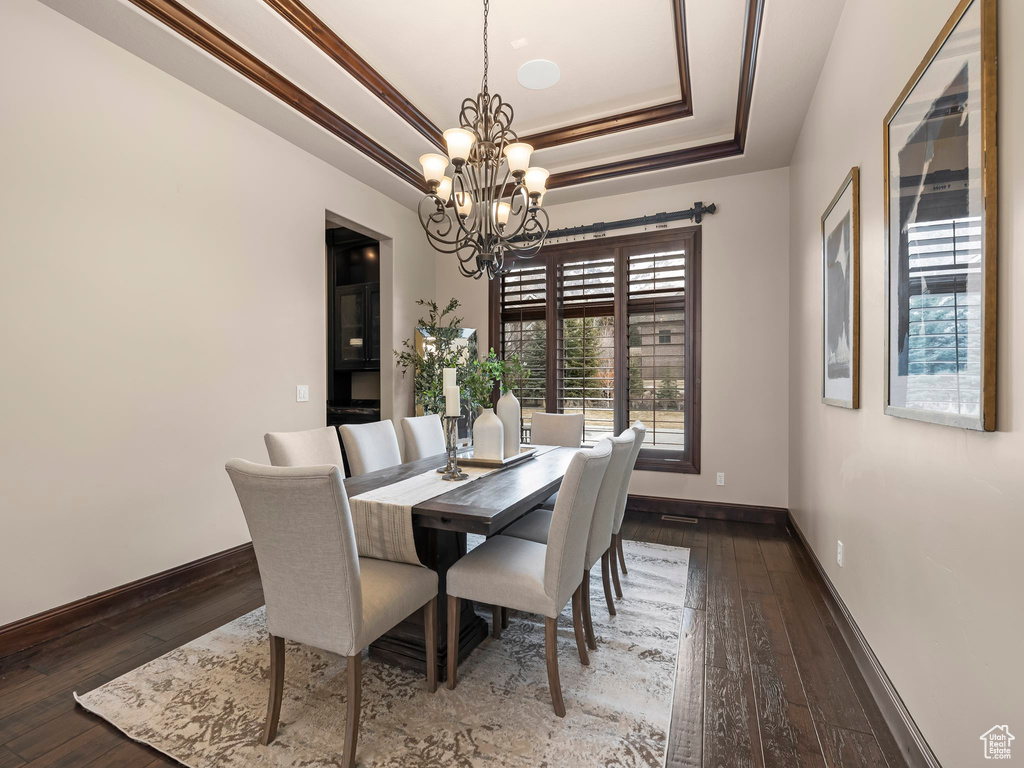 Dining space with an inviting chandelier, a tray ceiling, and dark hardwood / wood-style flooring