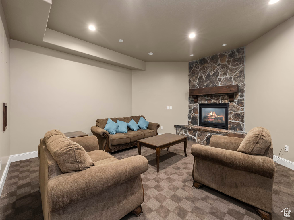 Living room featuring a stone fireplace and dark colored carpet