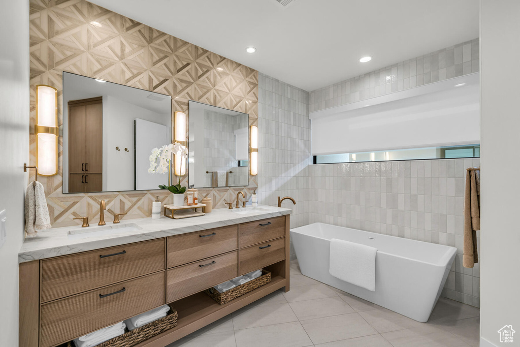 Bathroom featuring tile walls, dual bowl vanity, backsplash, tile flooring, and a bath