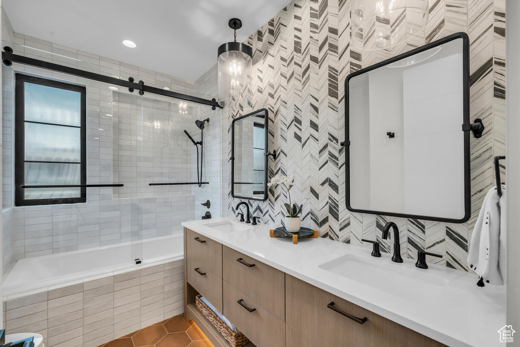 Bathroom featuring shower / bath combination with glass door, tile walls, tile flooring, and dual vanity