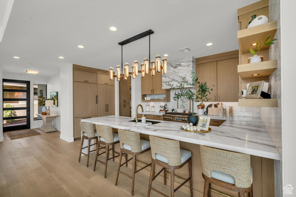 Kitchen with a kitchen bar, pendant lighting, light hardwood / wood-style flooring, and sink