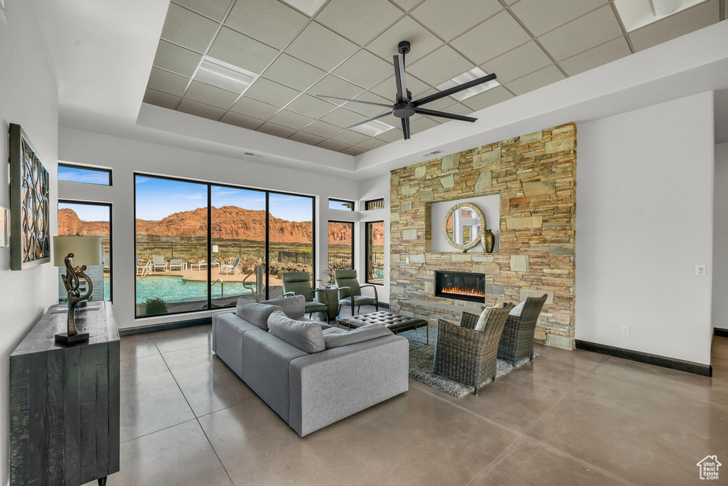Tiled living room with a raised ceiling, a fireplace, ceiling fan, and a mountain view