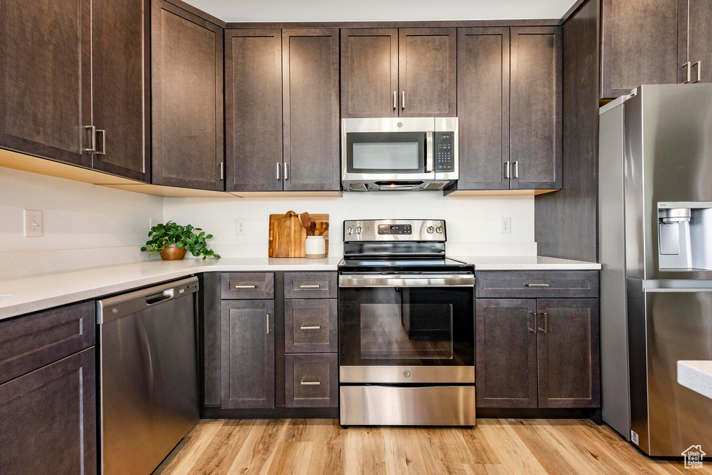 Kitchen featuring dark brown cabinets, appliances with stainless steel finishes, and light hardwood / wood-style flooring