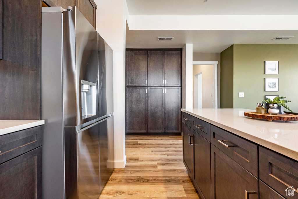 Kitchen featuring dark brown cabinetry, light hardwood / wood-style flooring, and stainless steel fridge