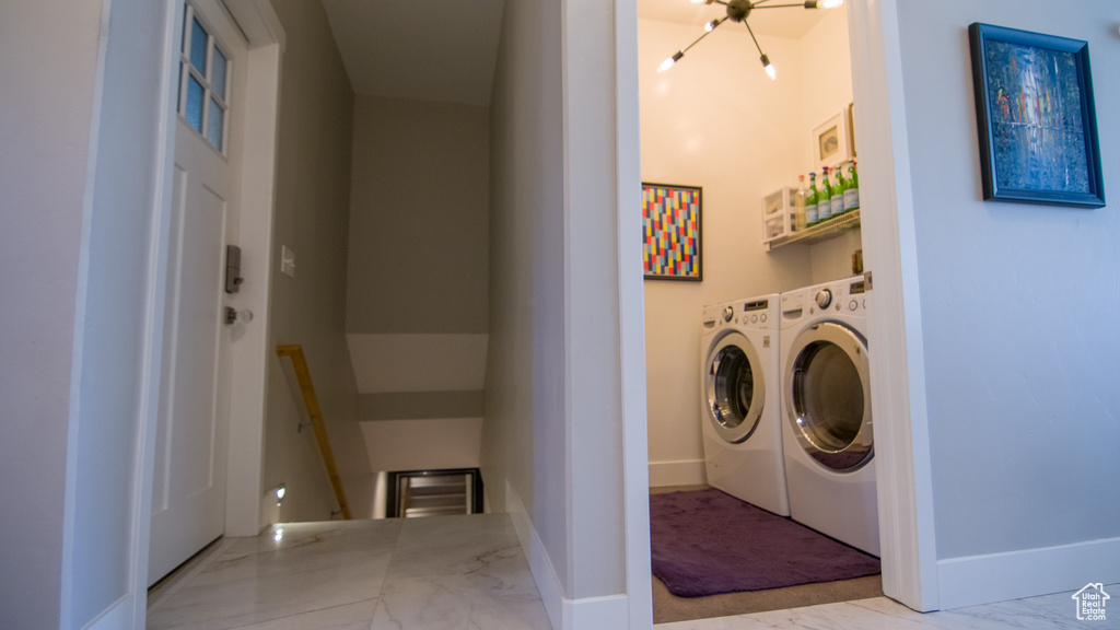 Laundry area with a notable chandelier, light tile floors, and washer and dryer