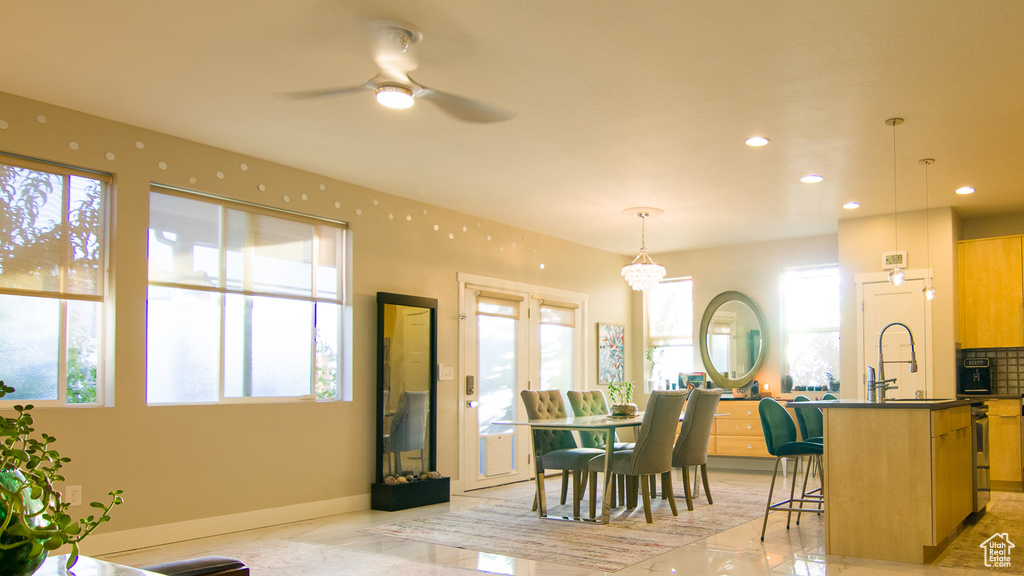 Dining space with light tile floors, ceiling fan with notable chandelier, and sink