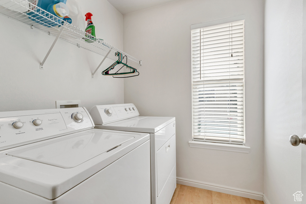 Laundry room featuring washing machine and dryer and light hardwood / wood-style floors