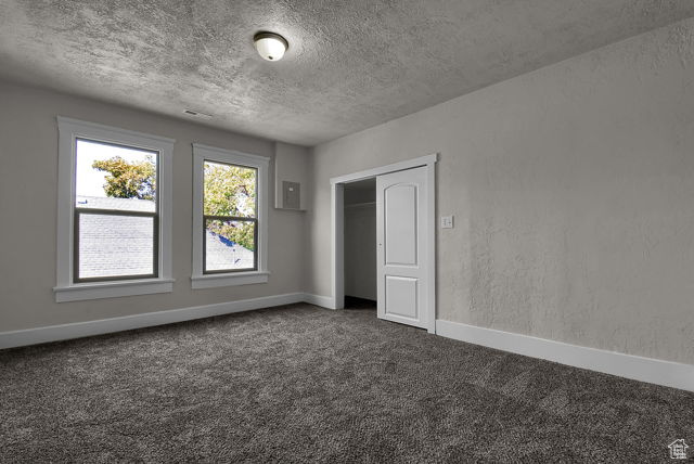 Interior space featuring a closet, a textured ceiling, and dark colored carpet