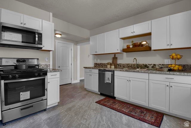Kitchen featuring white cabinetry, appliances with stainless steel finishes, light tile floors, and sink