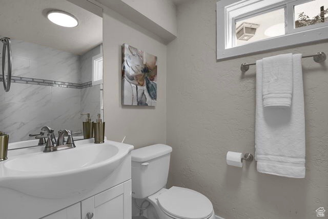 Bathroom featuring a wealth of natural light, toilet, and vanity with extensive cabinet space