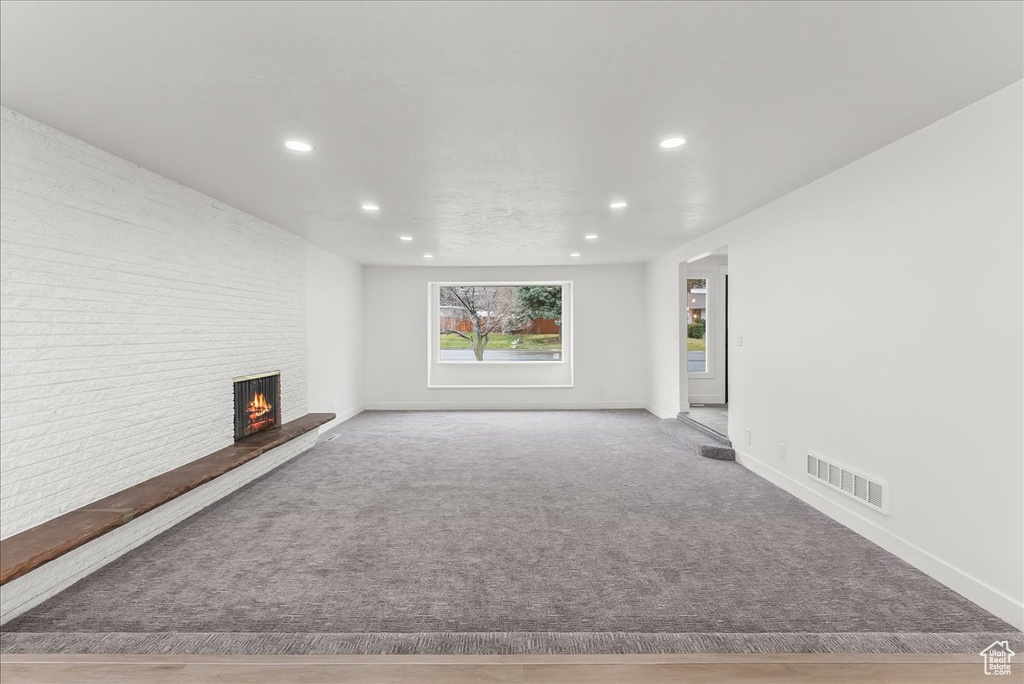 Unfurnished living room with brick wall and light hardwood / wood-style floors