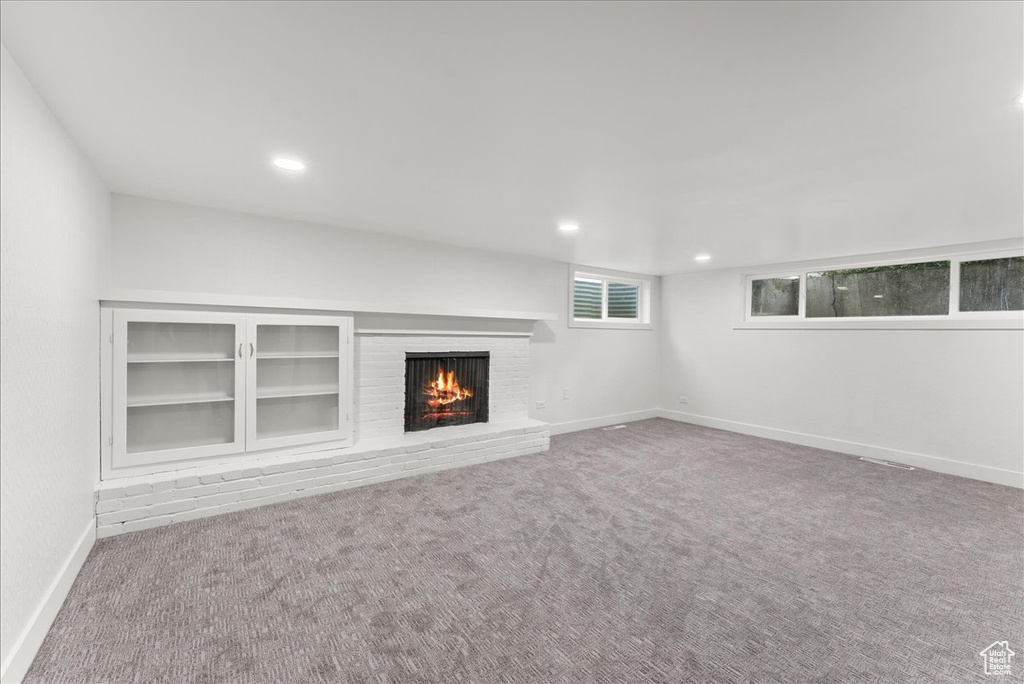 Unfurnished living room featuring light carpet and a brick fireplace