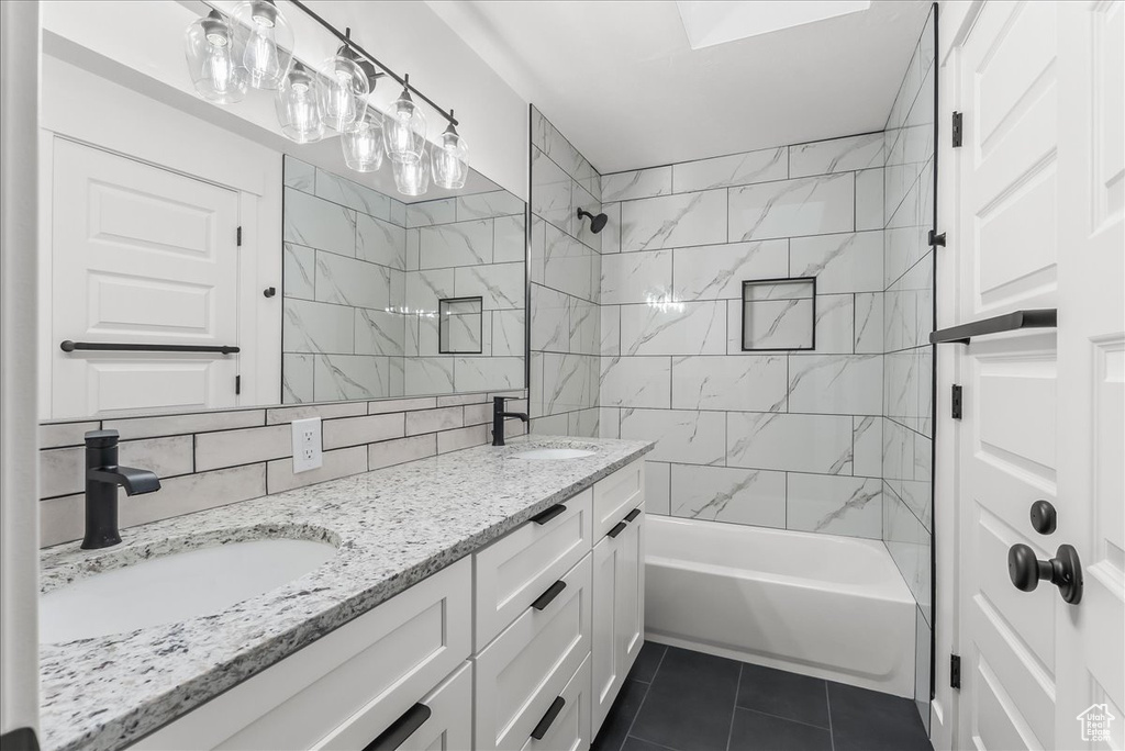 Bathroom with double sink, tile floors, tile walls, tiled shower / bath combo, and large vanity