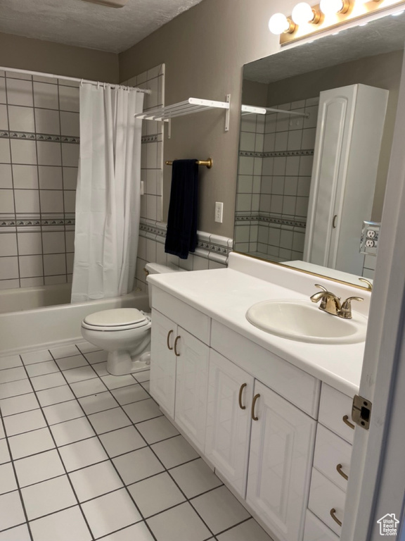 Full bathroom with tile floors, shower / tub combo, toilet, and vanity