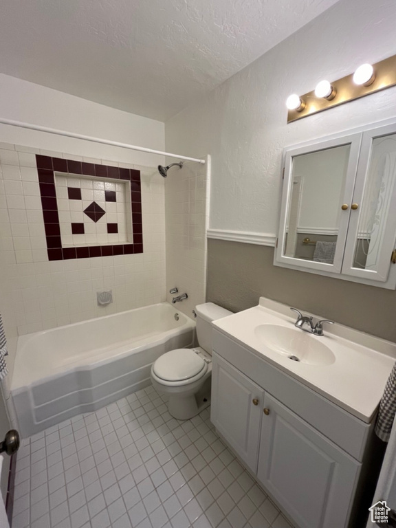 Full bathroom with tile floors, vanity, toilet, and tiled shower / bath combo