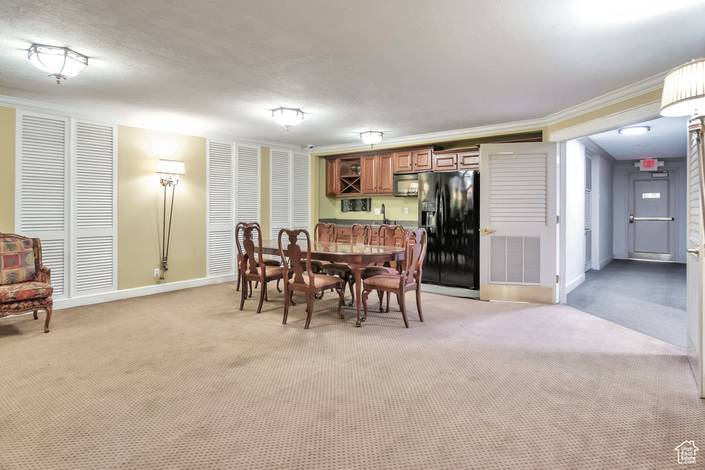 Carpeted dining space with ornamental molding