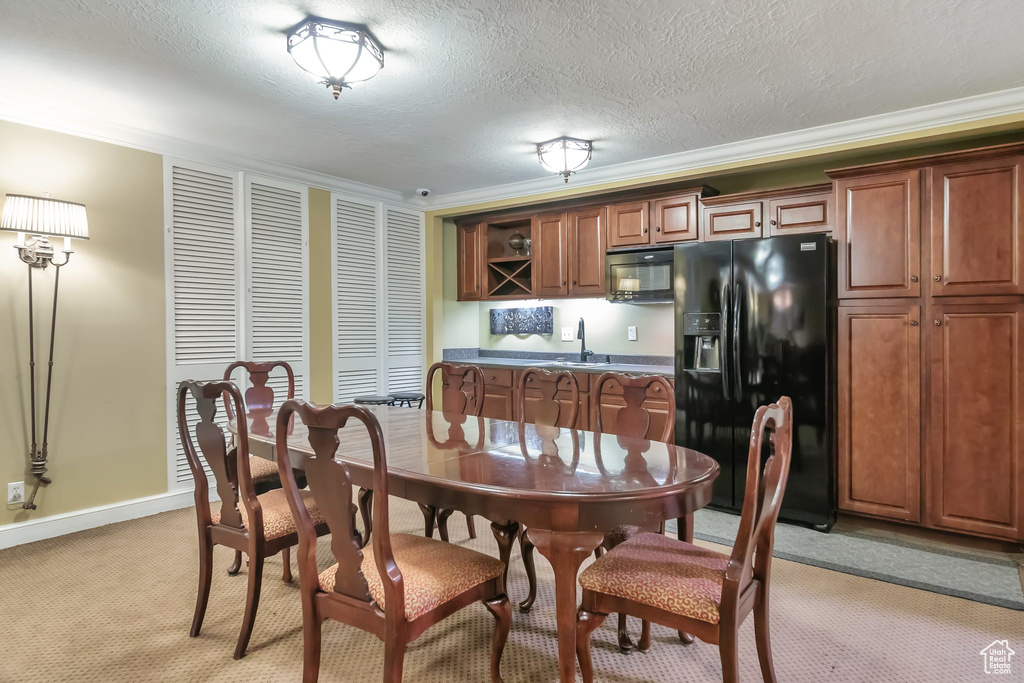 Dining space with light carpet, a textured ceiling, sink, and crown molding