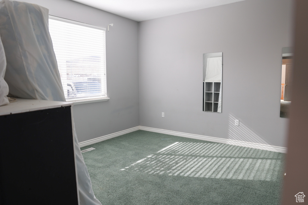 Empty room featuring a healthy amount of sunlight and dark carpet