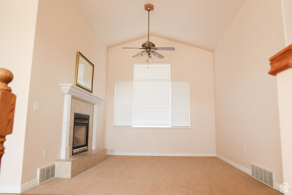 Unfurnished living room featuring light colored carpet, high vaulted ceiling, ceiling fan, and a fireplace