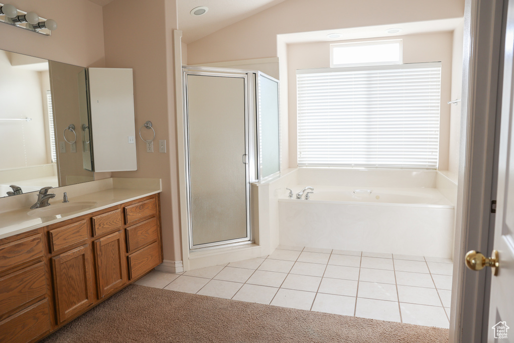 Bathroom with vanity, lofted ceiling, shower with separate bathtub, and tile floors